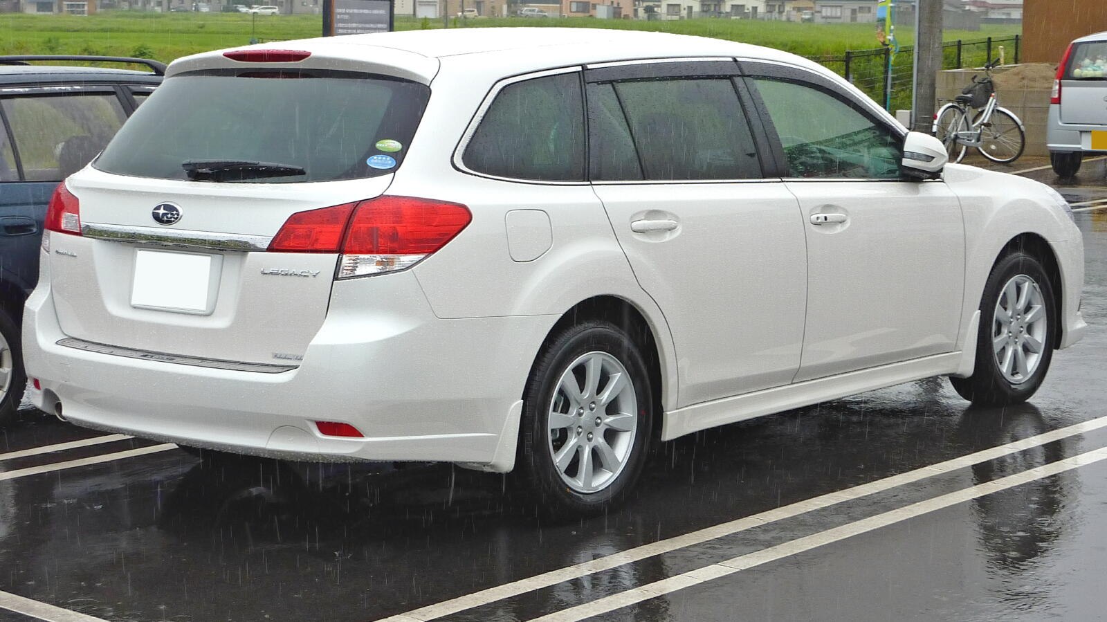 Rear side profile of a white station wagon with multi-spoke wheels