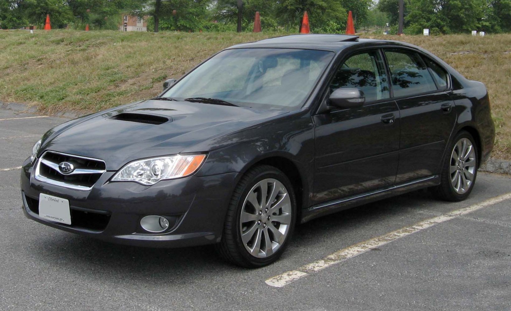 Sedan with hood scoop and multi-spoke alloy wheels parked outdoors