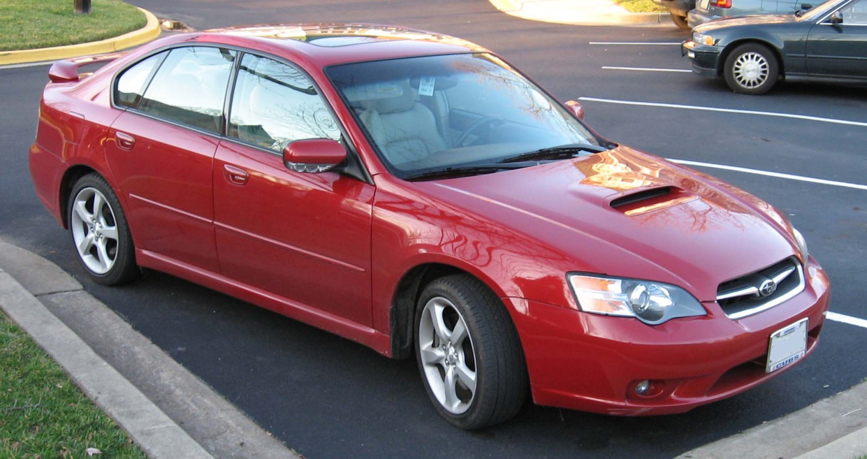 Red sedan with hood scoop, alloy wheels, and rear spoiler