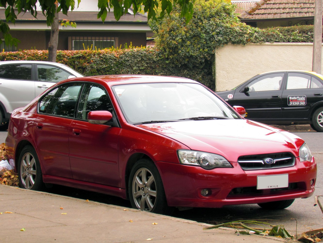 Red sedan with clear headlights and alloy wheels parked on street
