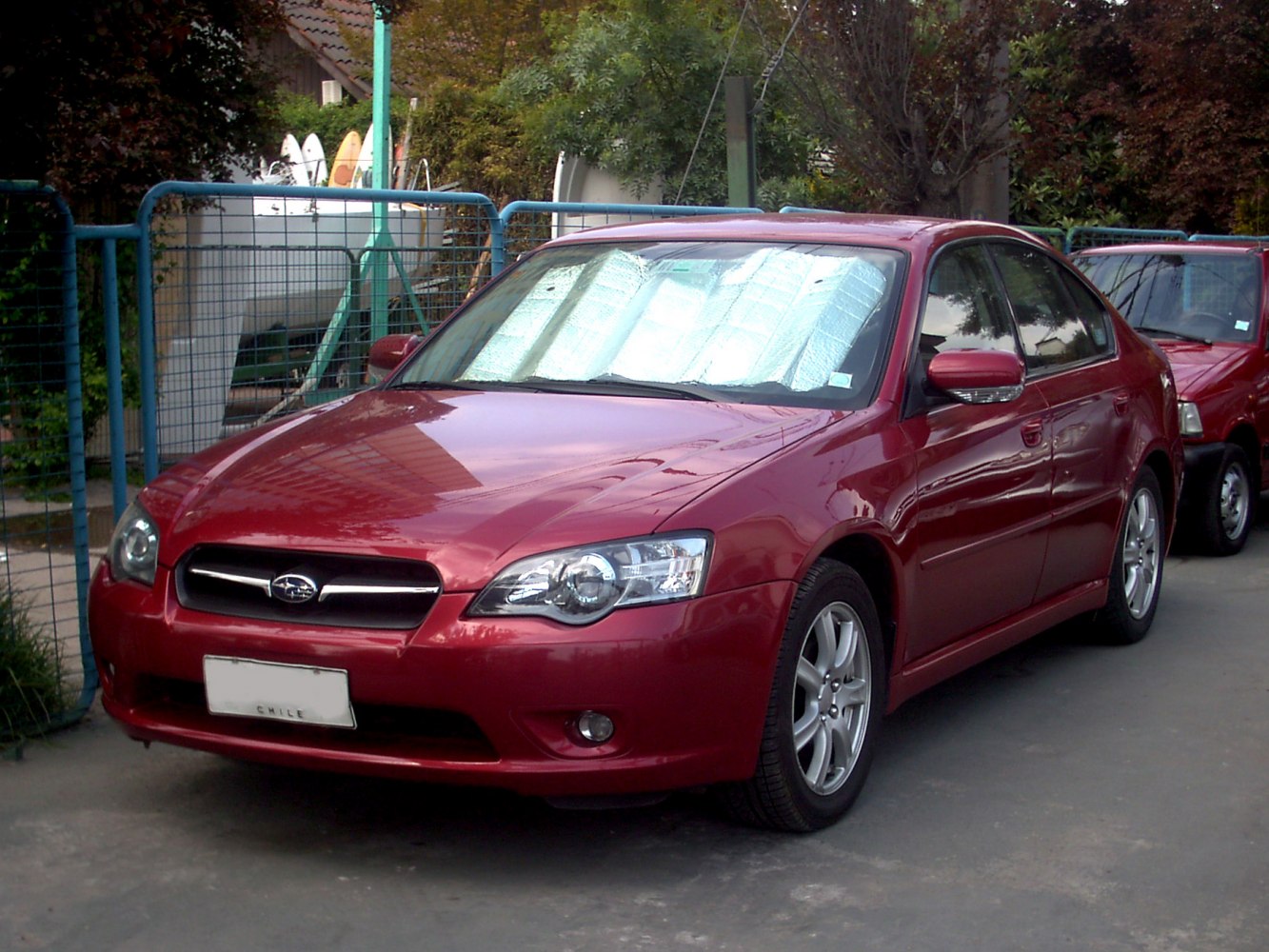 Red sedan with clear headlamps and alloy wheels parked with windshield sunshade