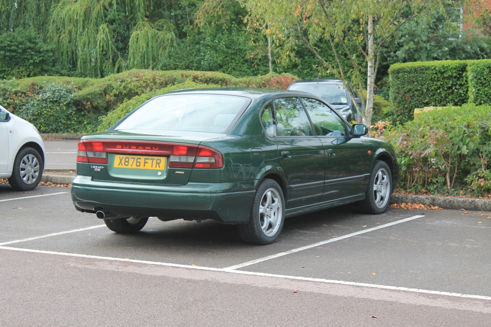 Rear and side view of green four-door sedan with horizontal taillights