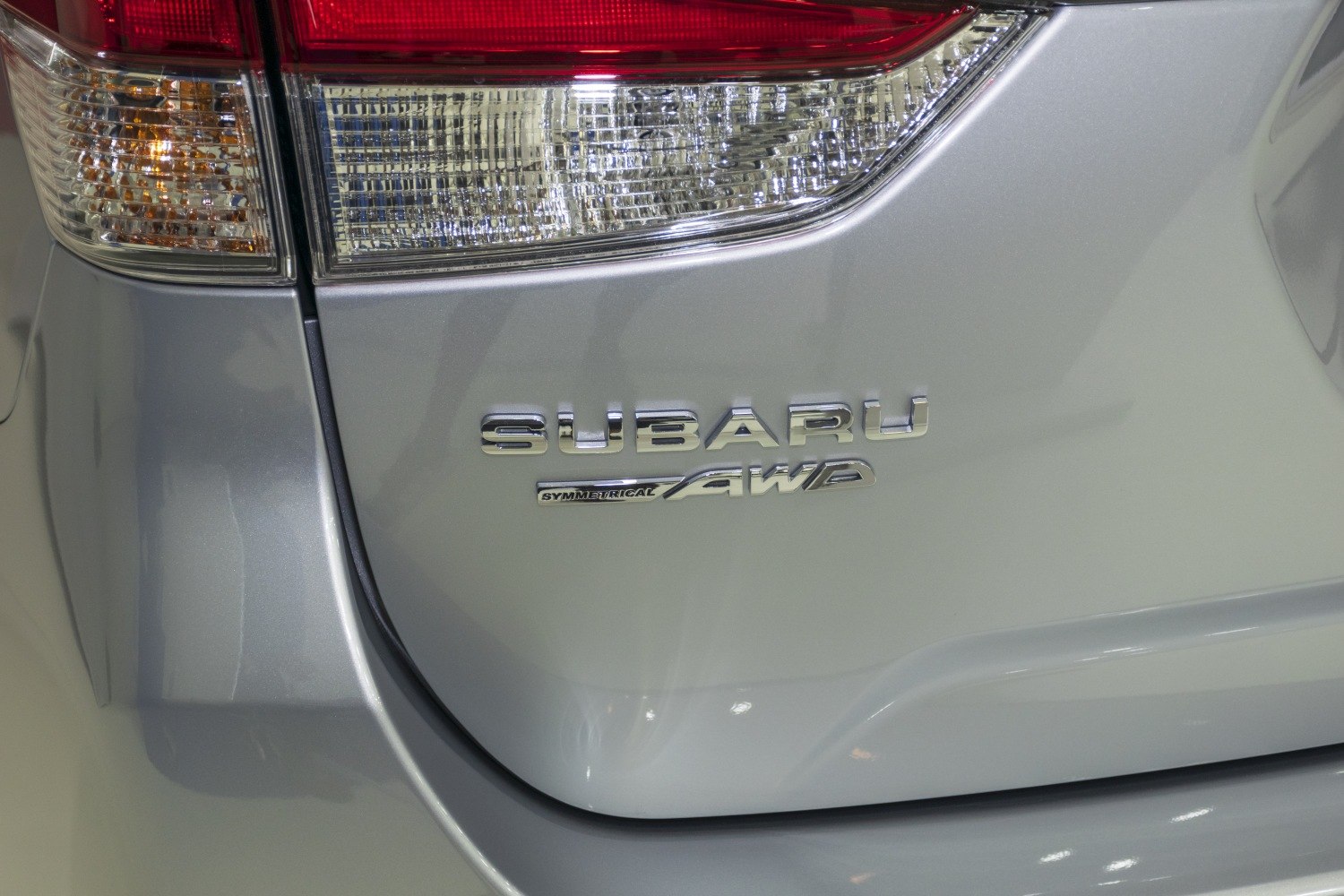 Close-up of rear tail light and Symmetrical AWD badge on silver car.