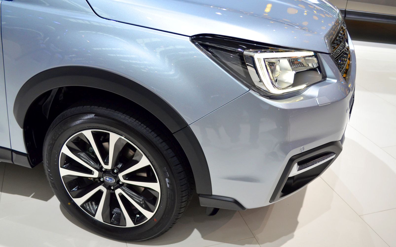 Close-up of front left alloy wheel and modern designer headlight