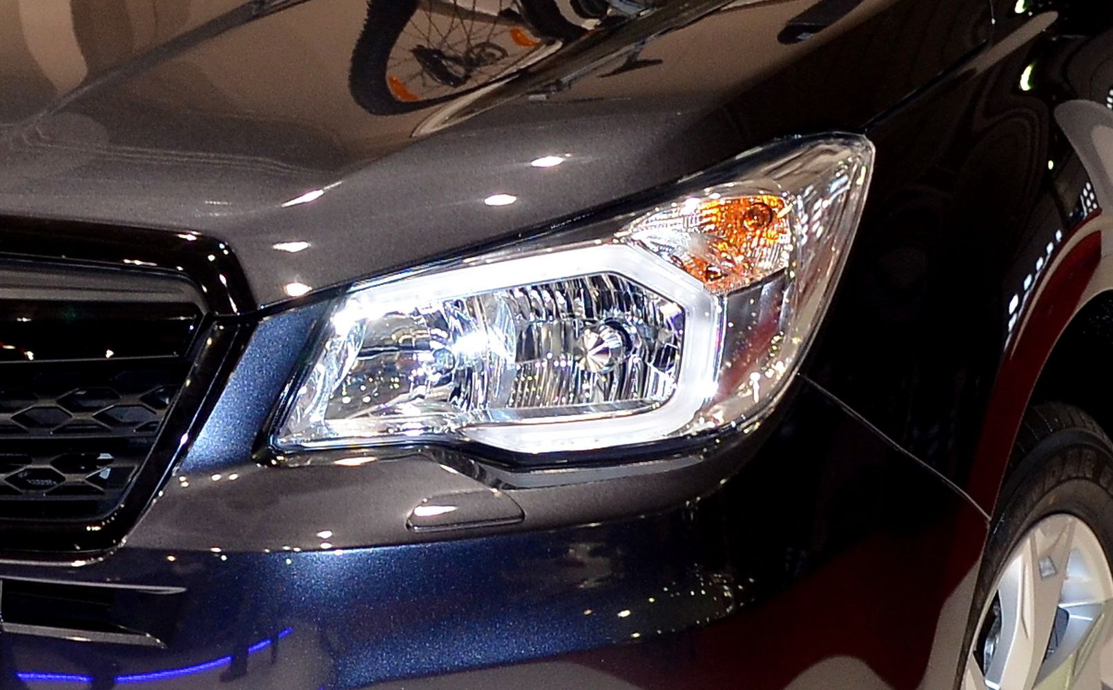 Close-up of front headlight and grille with honeycomb design.