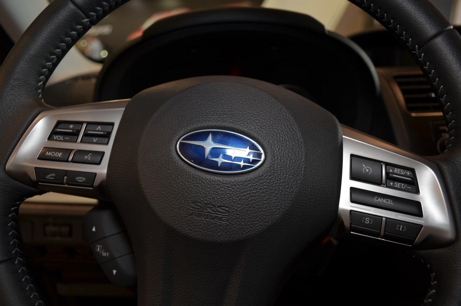 Steering wheel with control buttons and Subaru emblem