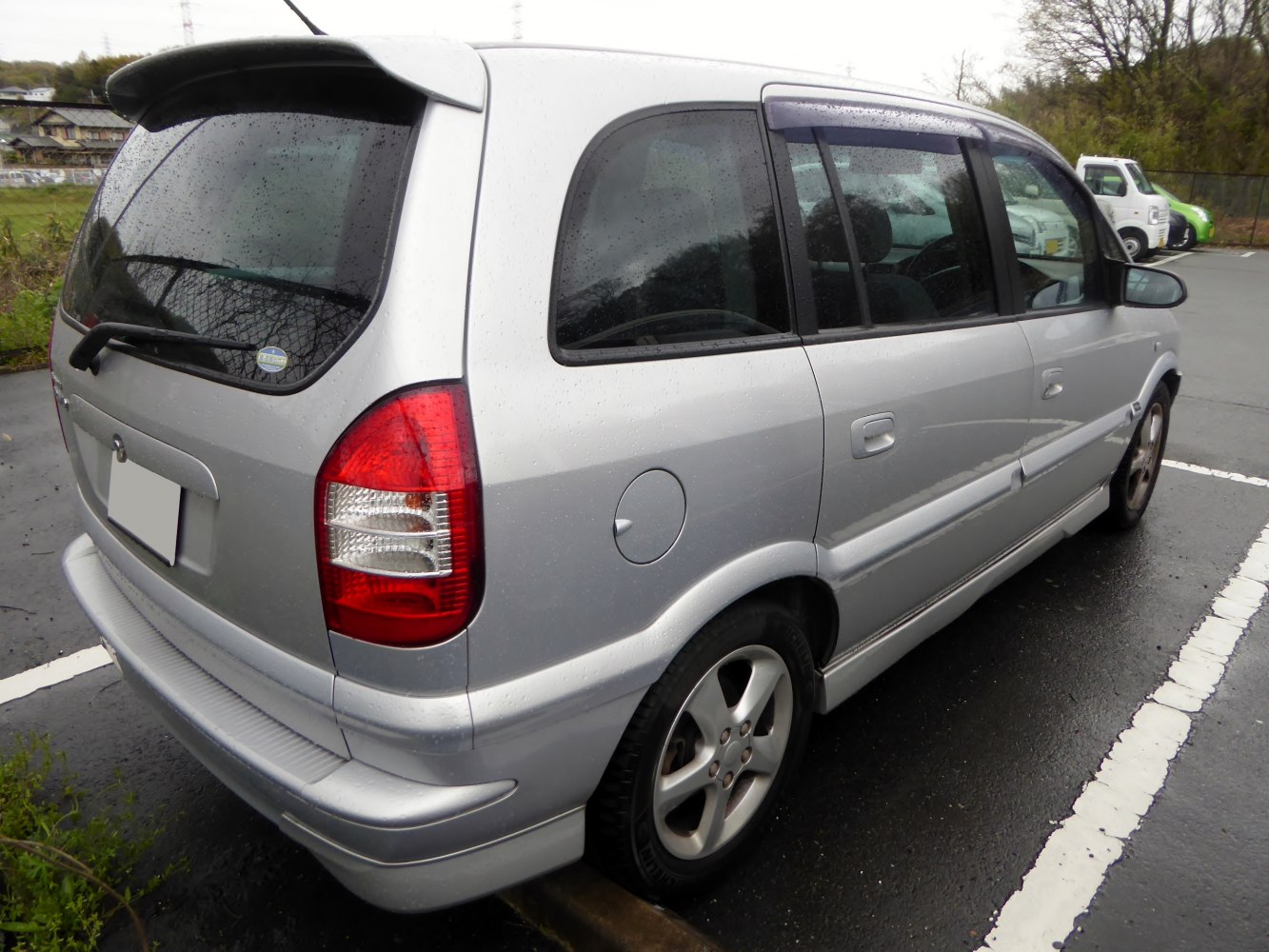 Silver compact MPV rear-side view with taillights and rear spoiler