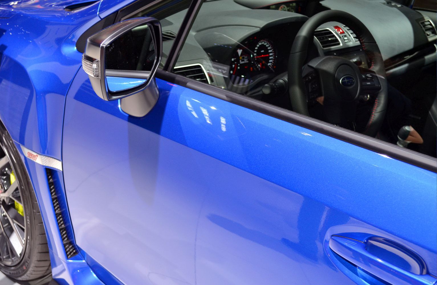 Blue car side door, side mirror, and interior steering wheel close-up