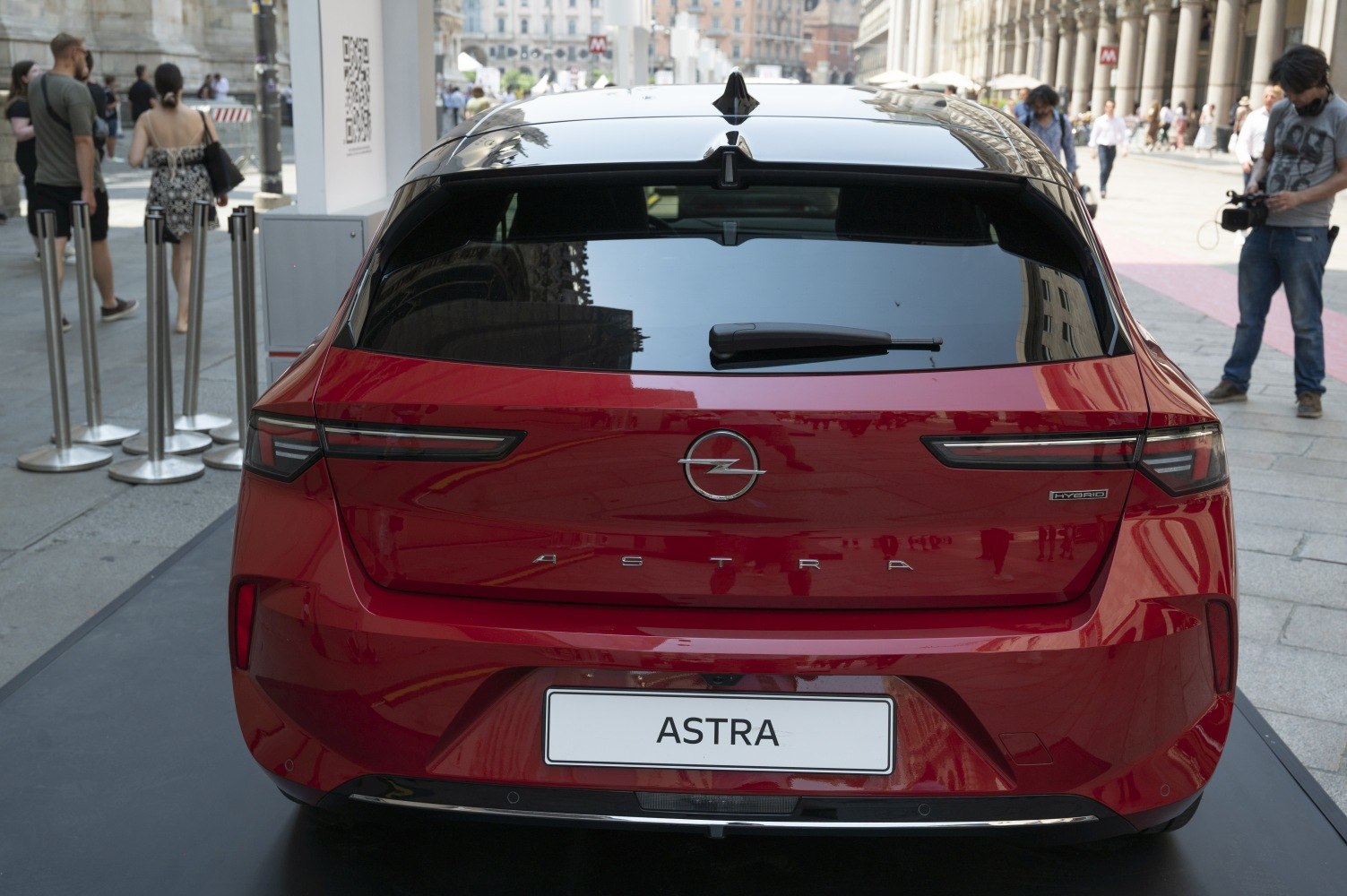 Rear view of red hatchback with hybrid badge and modern taillights.