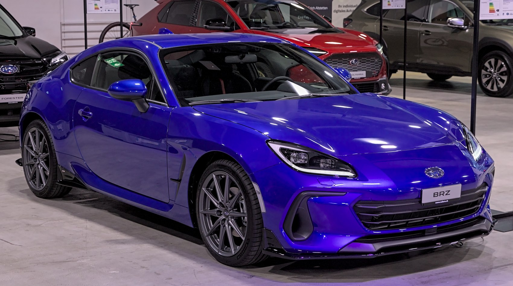 Blue sports coupe showing front and side aerodynamic design, sleek headlights, and sporty wheels