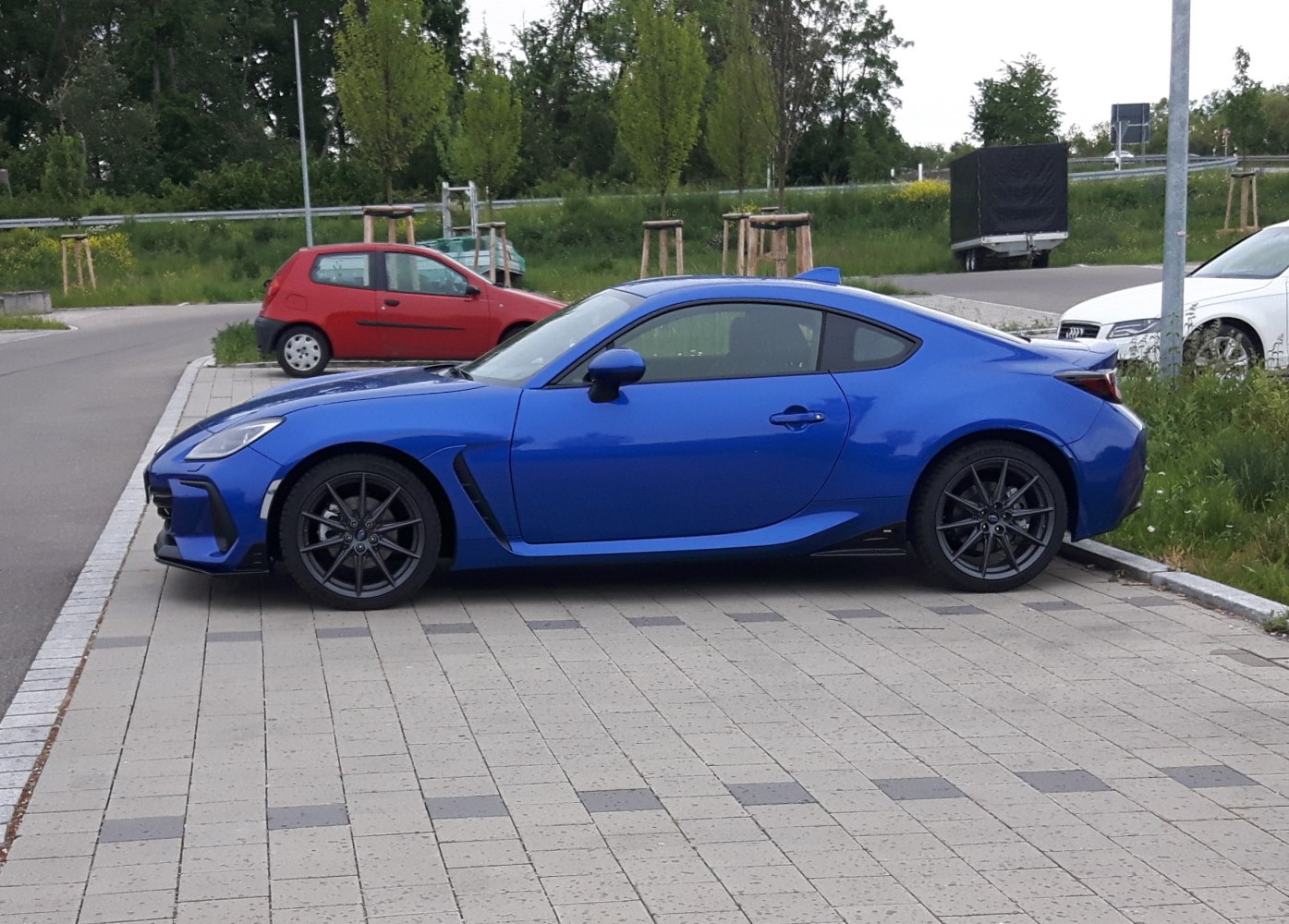 Sporty blue coupe with aerodynamic lines and dark multi-spoke wheels
