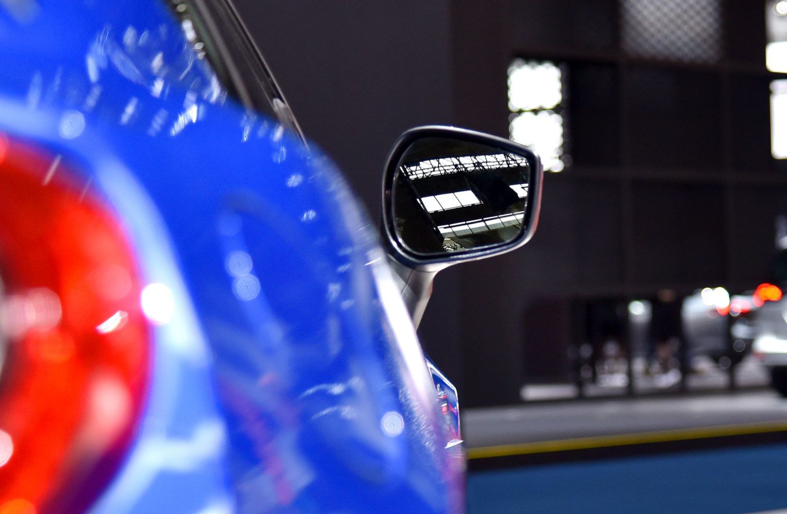 Close-up of side mirror and rear light on glossy blue coupe