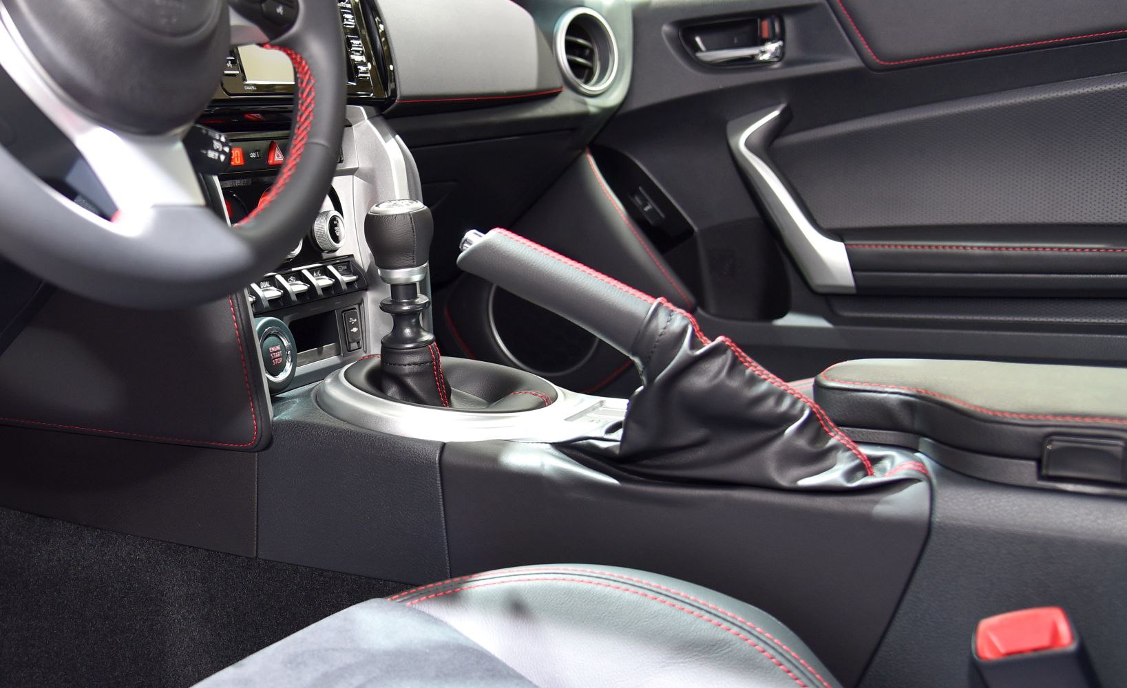 Manual gear shifter and leather handbrake with red stitching in sport interior