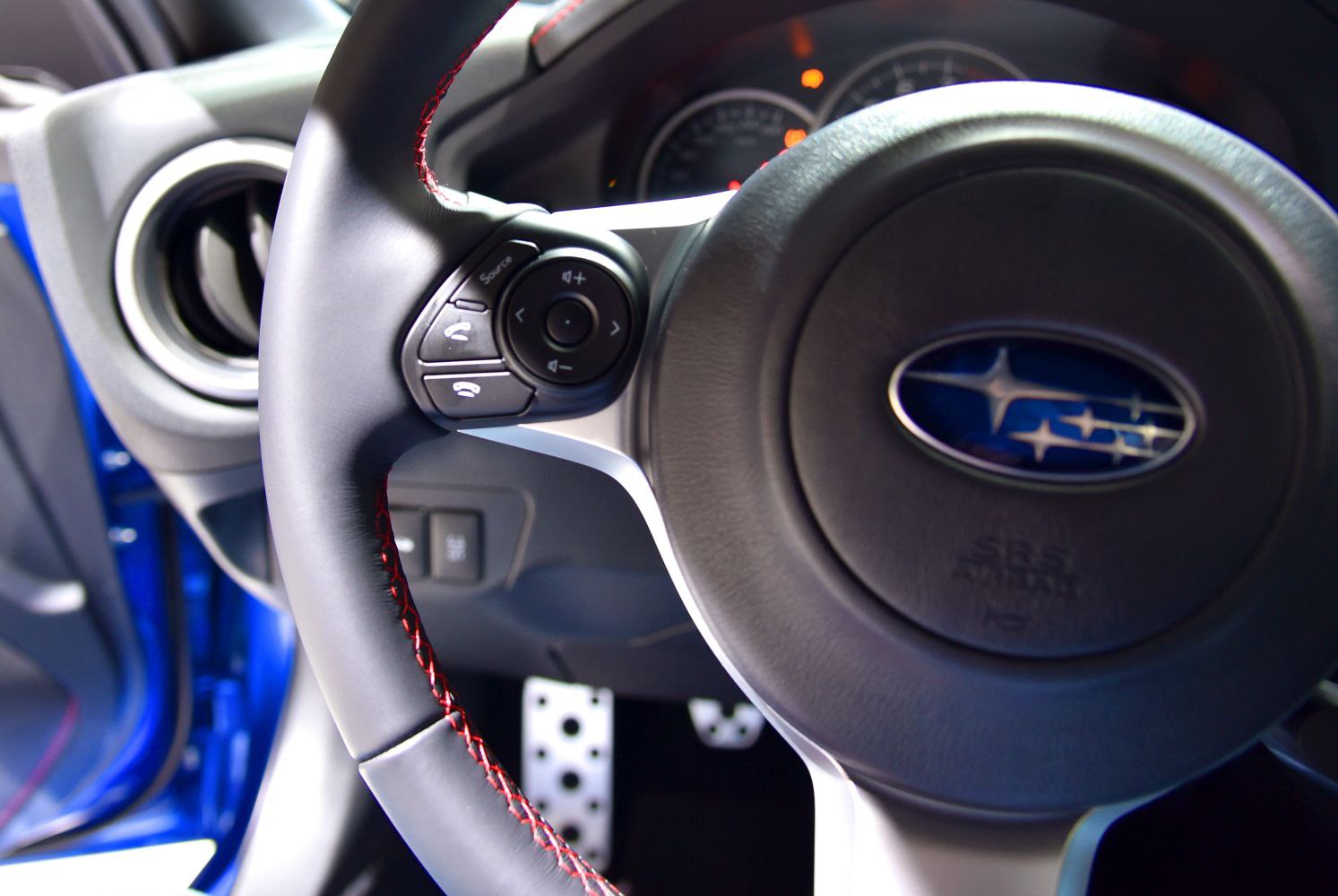 Steering wheel with control buttons and red stitching in sporty design