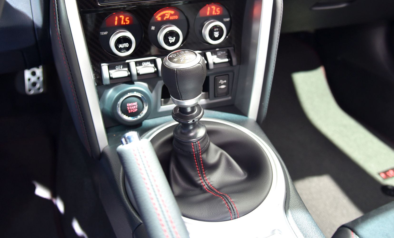 Manual gear stick with red stitching and digital climate control panel