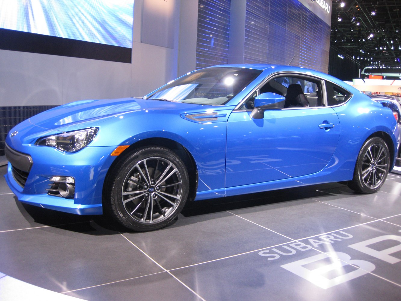 Blue sports coupe side view with aerodynamic vents and alloy wheels