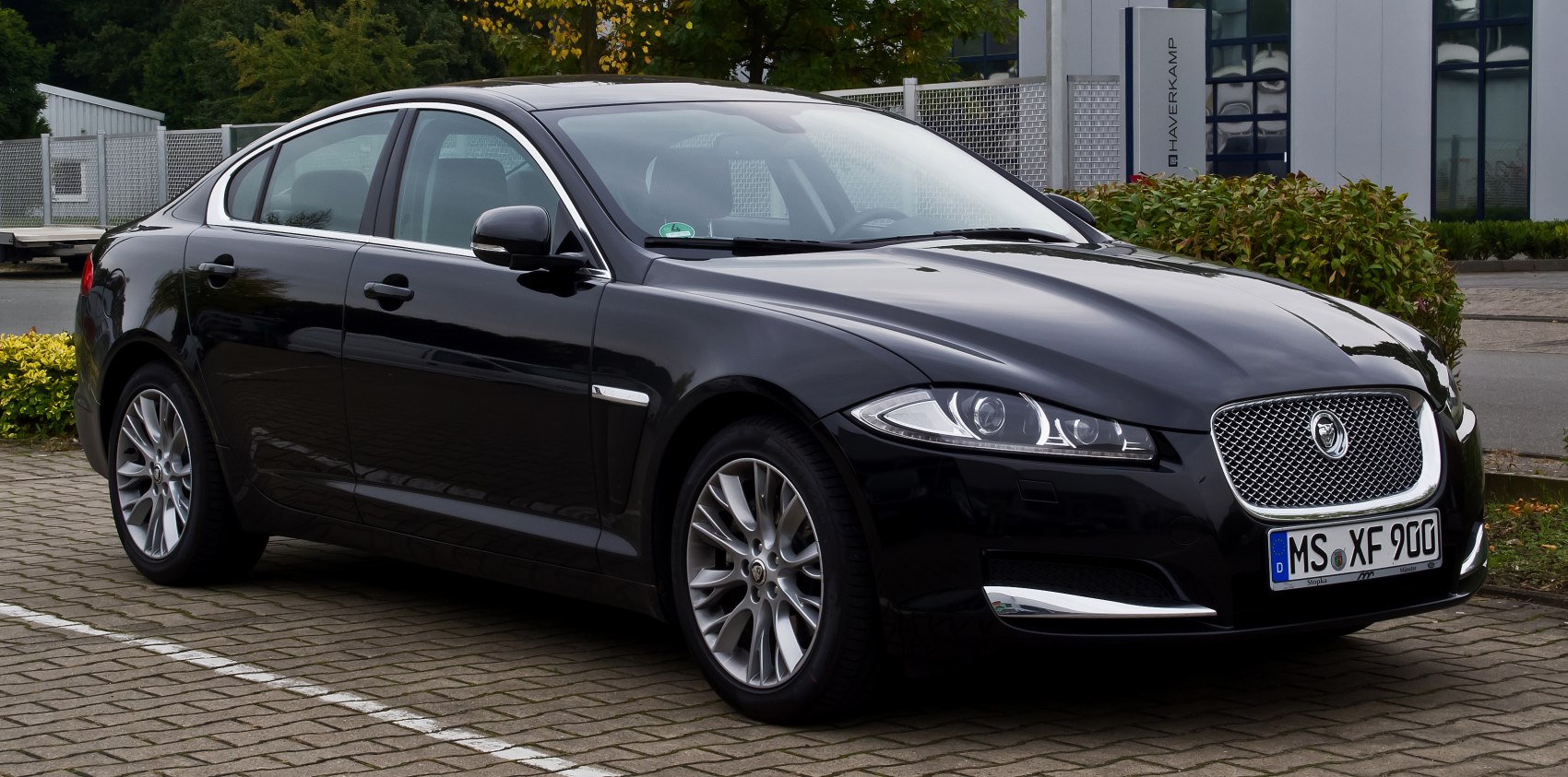 Black sedan with chrome mesh grille and multi-spoke alloy wheels