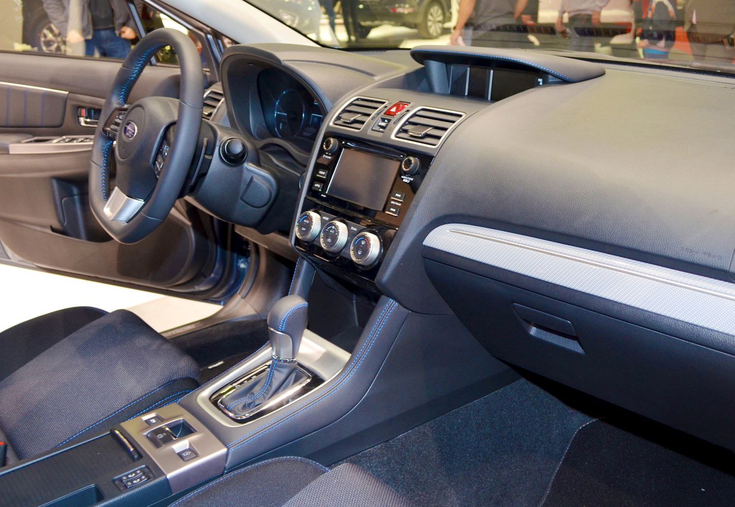 Car interior with dashboard, steering wheel, touchscreen, and gear shift.