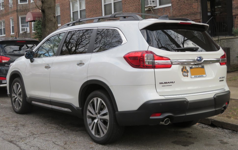 Rear side of a white mid-size SUV with roof rails and dual exhaust