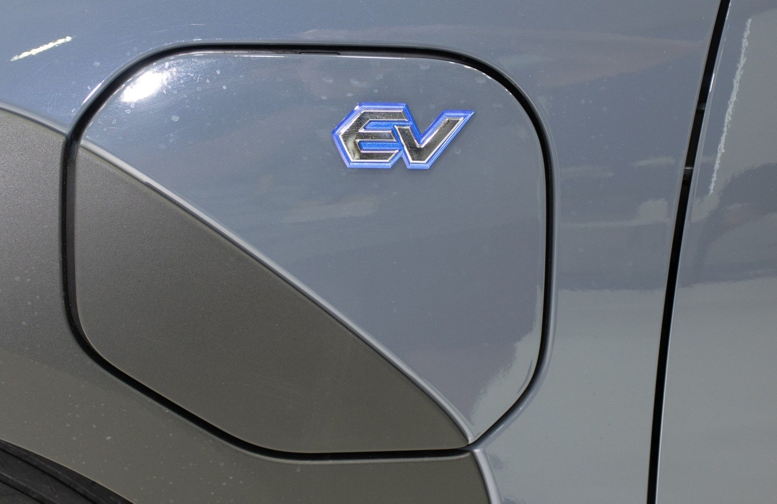 Close-up of electric vehicle charging port with EV badge