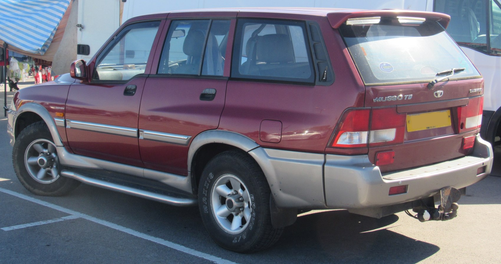 Rear side view of a rugged SUV with silver lower cladding and tow hitch