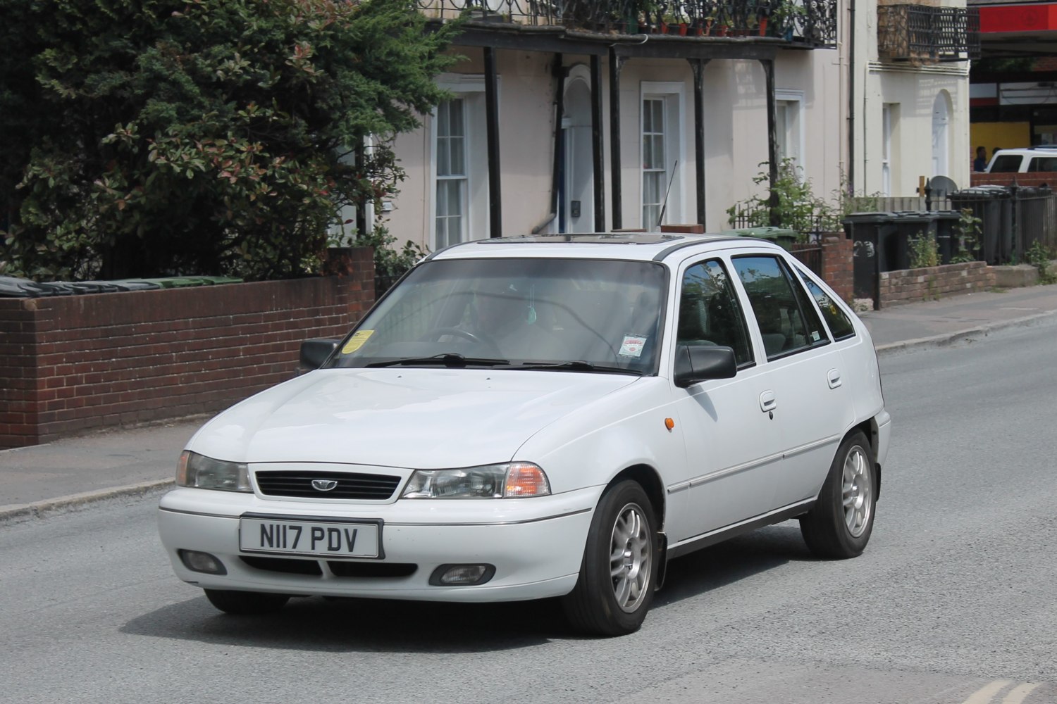 Compact hatchback with quad headlights, alloy wheels, rooftop antenna