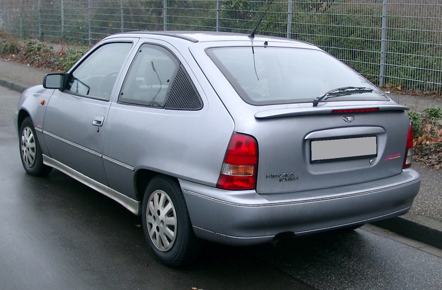 Rear and side view of a compact hatchback with a rear spoiler and unique triangular window.