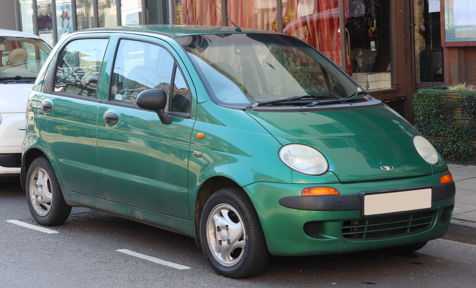 Compact five-door hatchback with rounded headlights and black side mirrors.