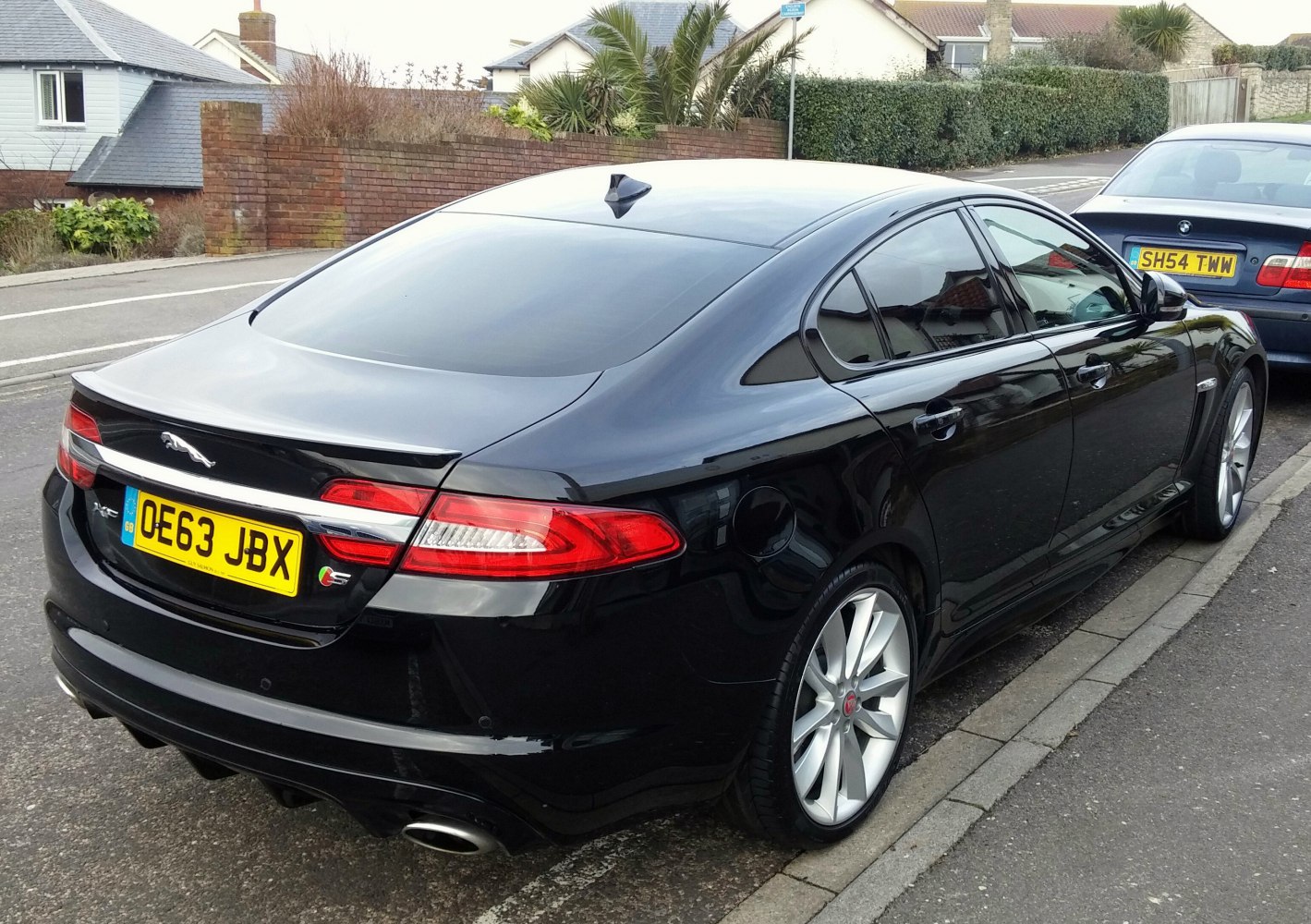 Black luxury sedan rear with dual exhaust and spoiler