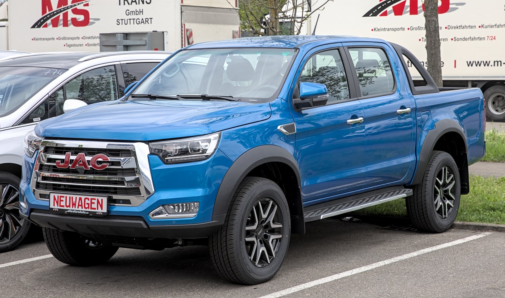 Blue double cab pickup with prominent chrome grille and alloy wheels