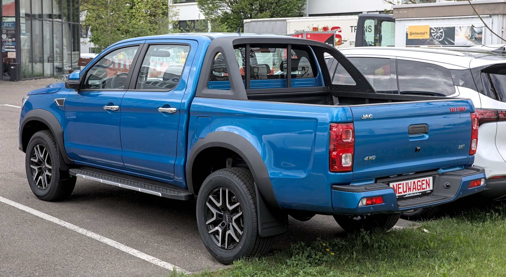 Blue double-cab pickup truck bed with black roll bar and alloy wheels.