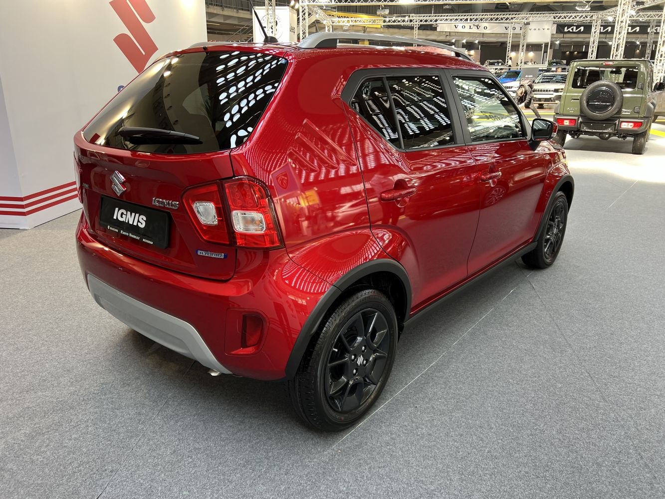 Rear-side view of compact red crossover with hybrid badge and black wheels