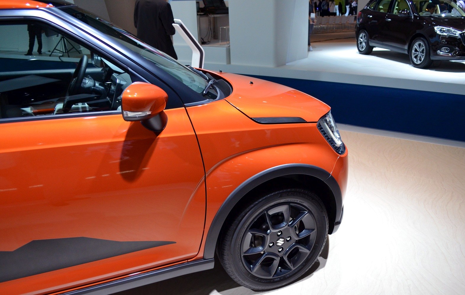 Front side view of orange compact hatchback with black alloy wheels