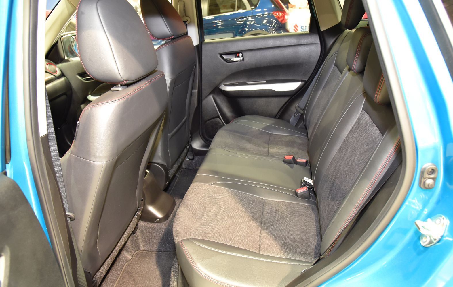 Rear seating with leather and fabric upholstery featuring red stitching.