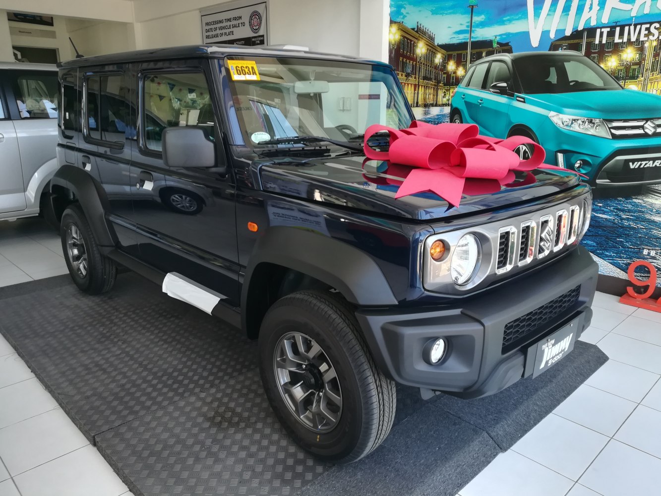 Front and side view of compact SUV with red hood bow