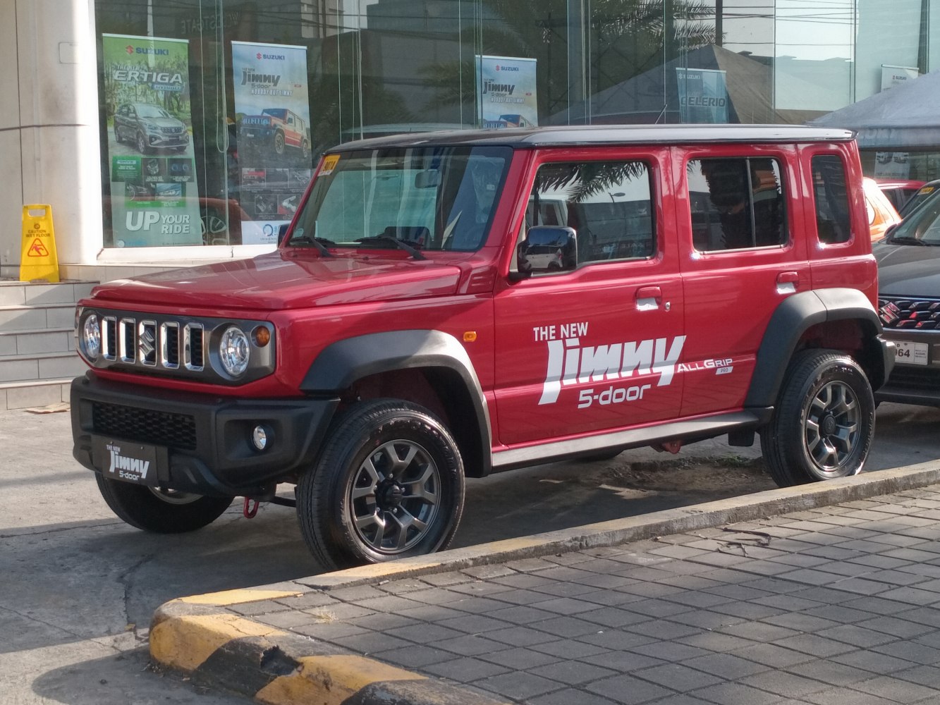 Red 5-door SUV with boxy design, round headlights, and black wheel arches