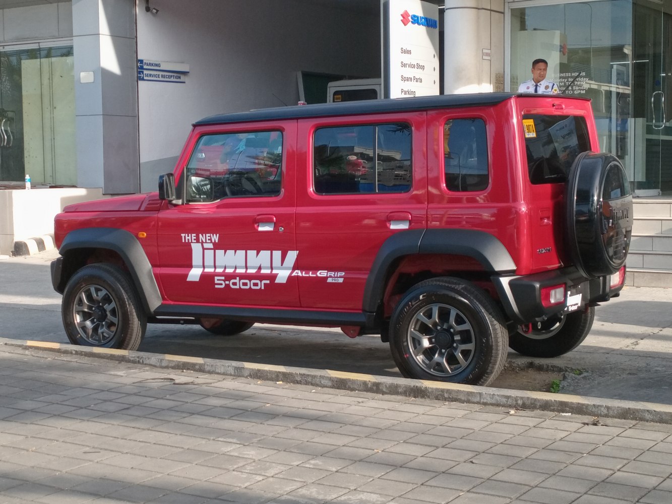 Side view of red 5-door SUV with spare tire cover and rugged features