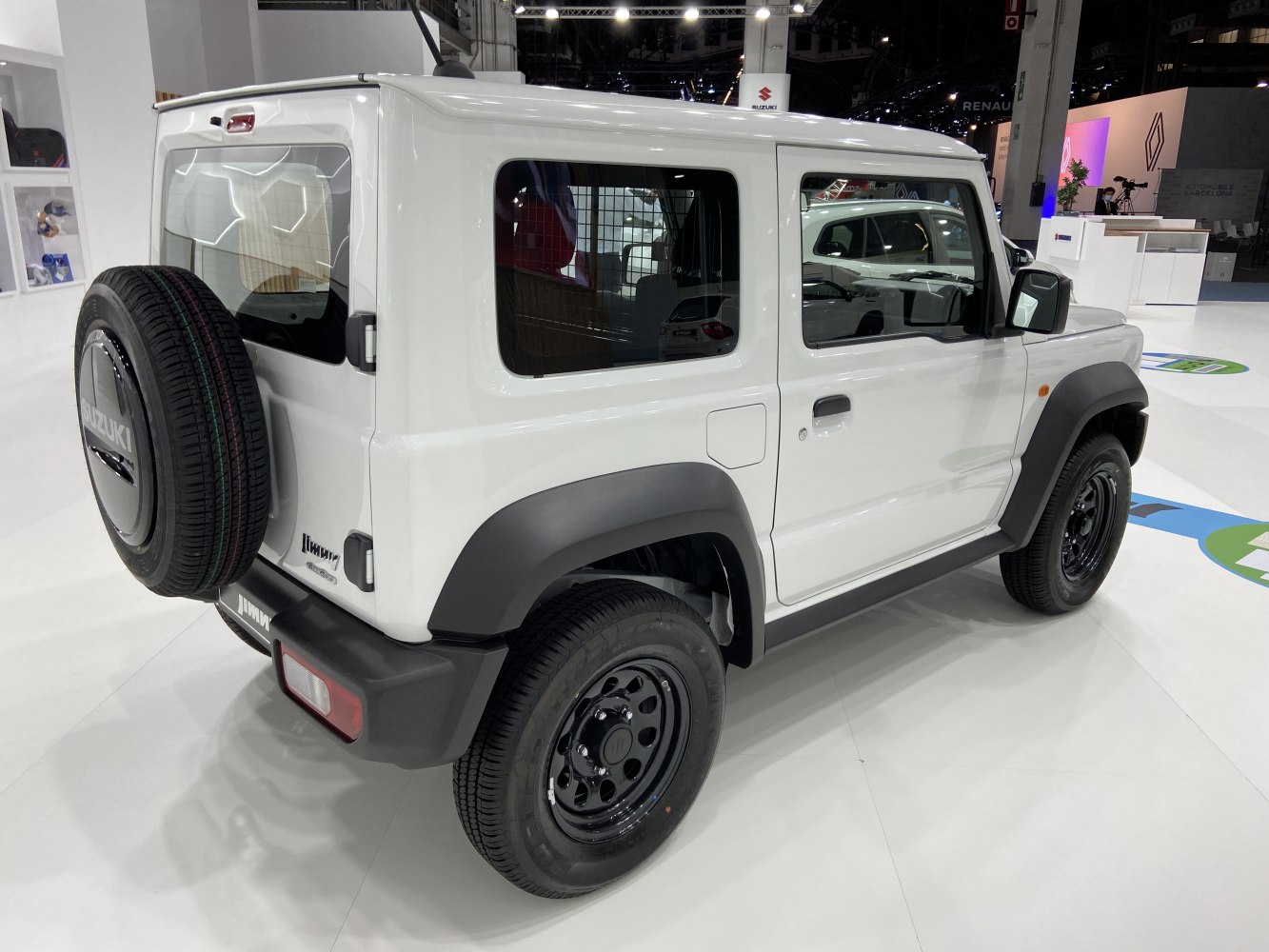 Rear side view of a white off-road SUV with a spare tire on the back