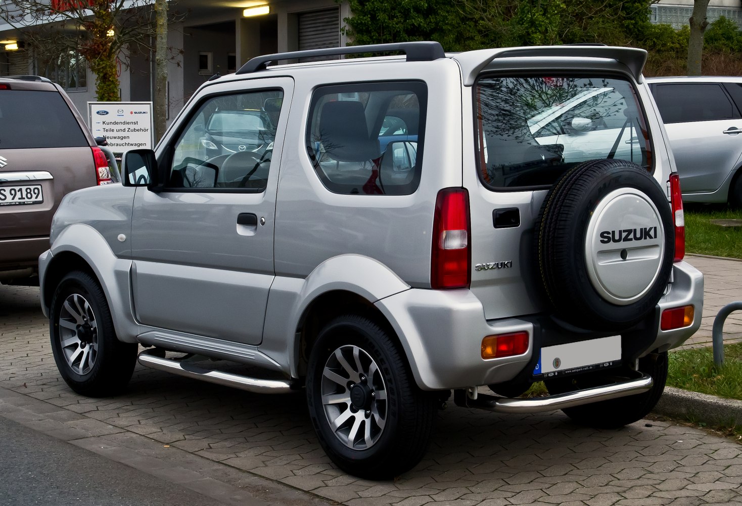 Rear side view of silver compact SUV with spare tire mounted on rear door