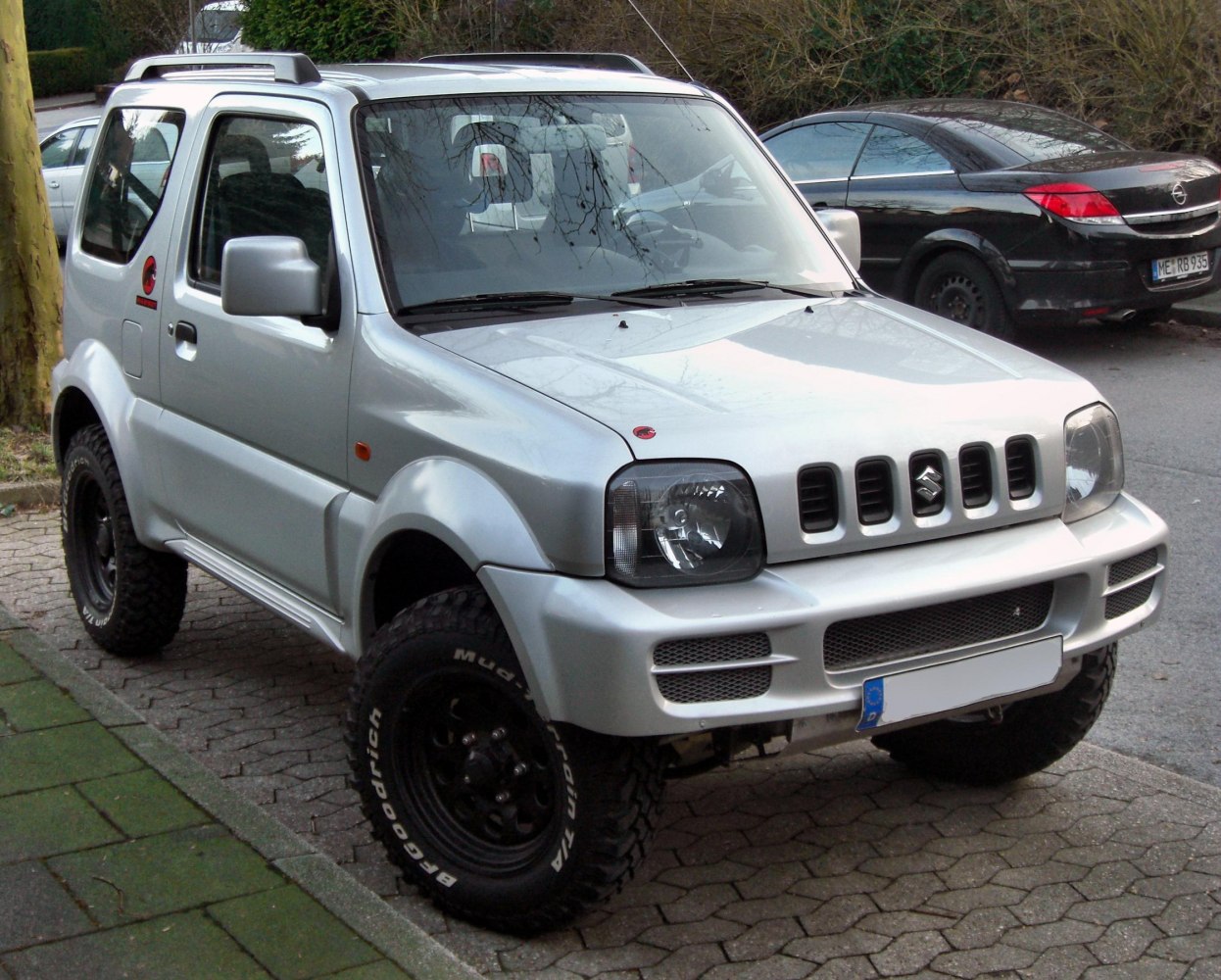 Front-side view of rugged off-road vehicle with distinctive grille and mud tires.
