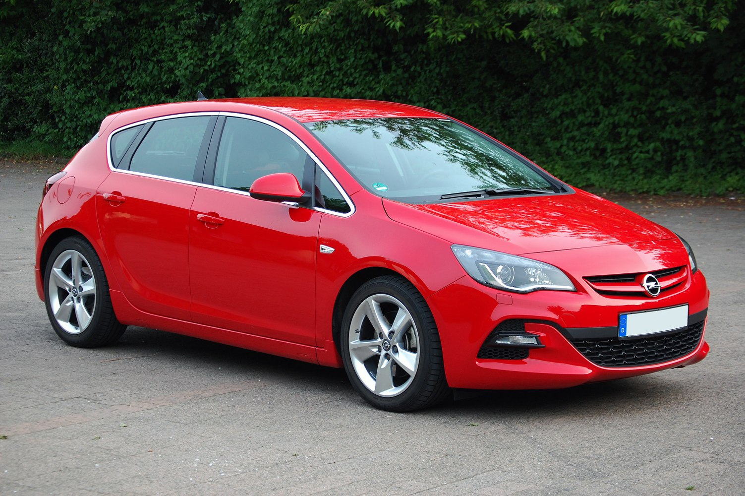Front side view of red hatchback with alloy wheels and sleek headlights