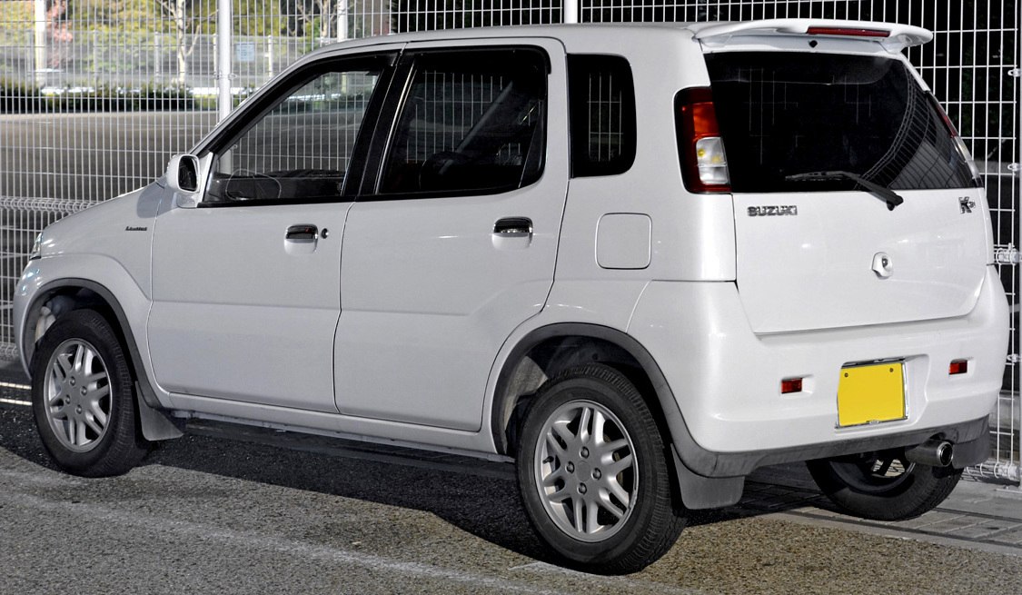 Compact hatchback rear-side view with rear spoiler and five-door layout