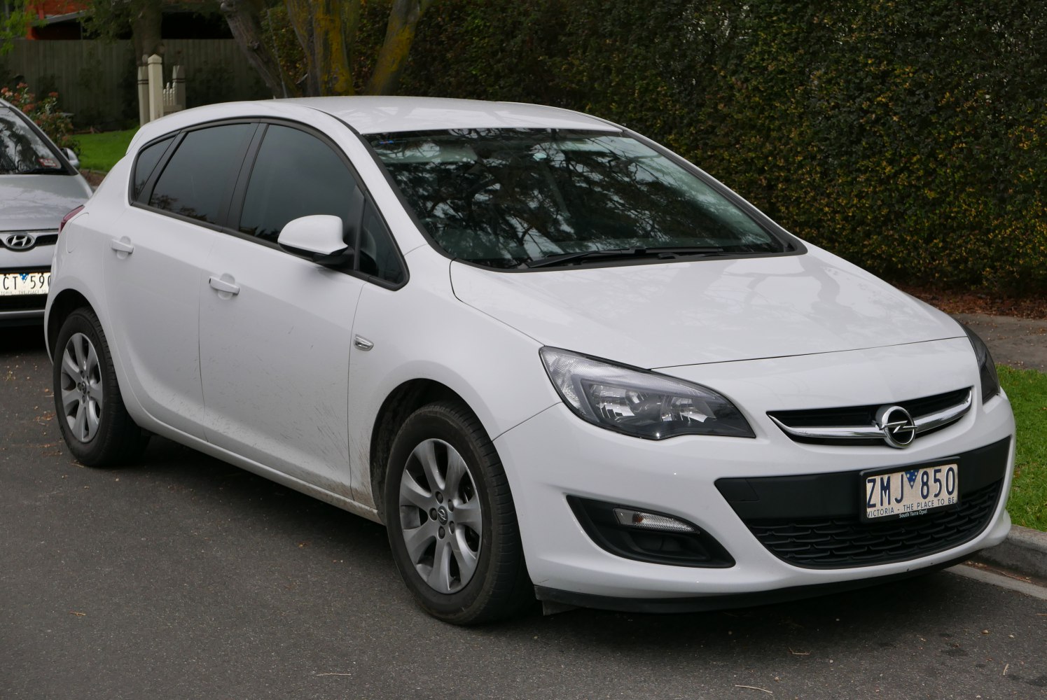 White hatchback showing front side with headlights and alloy wheels