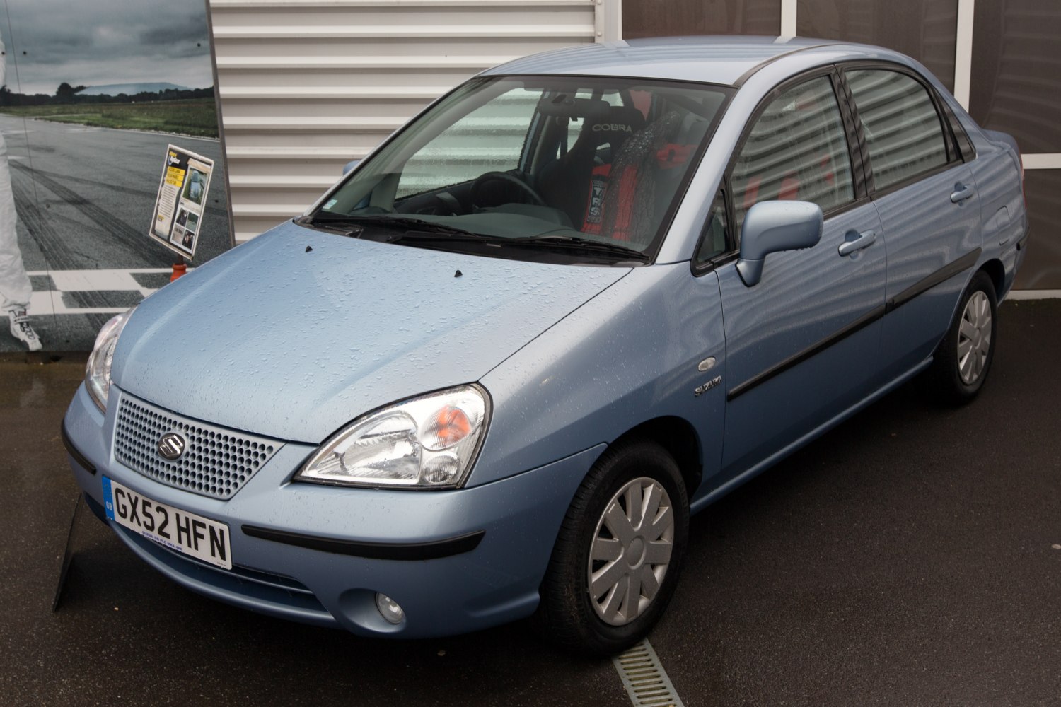 Blue compact sedan front-side view with detailed headlights.