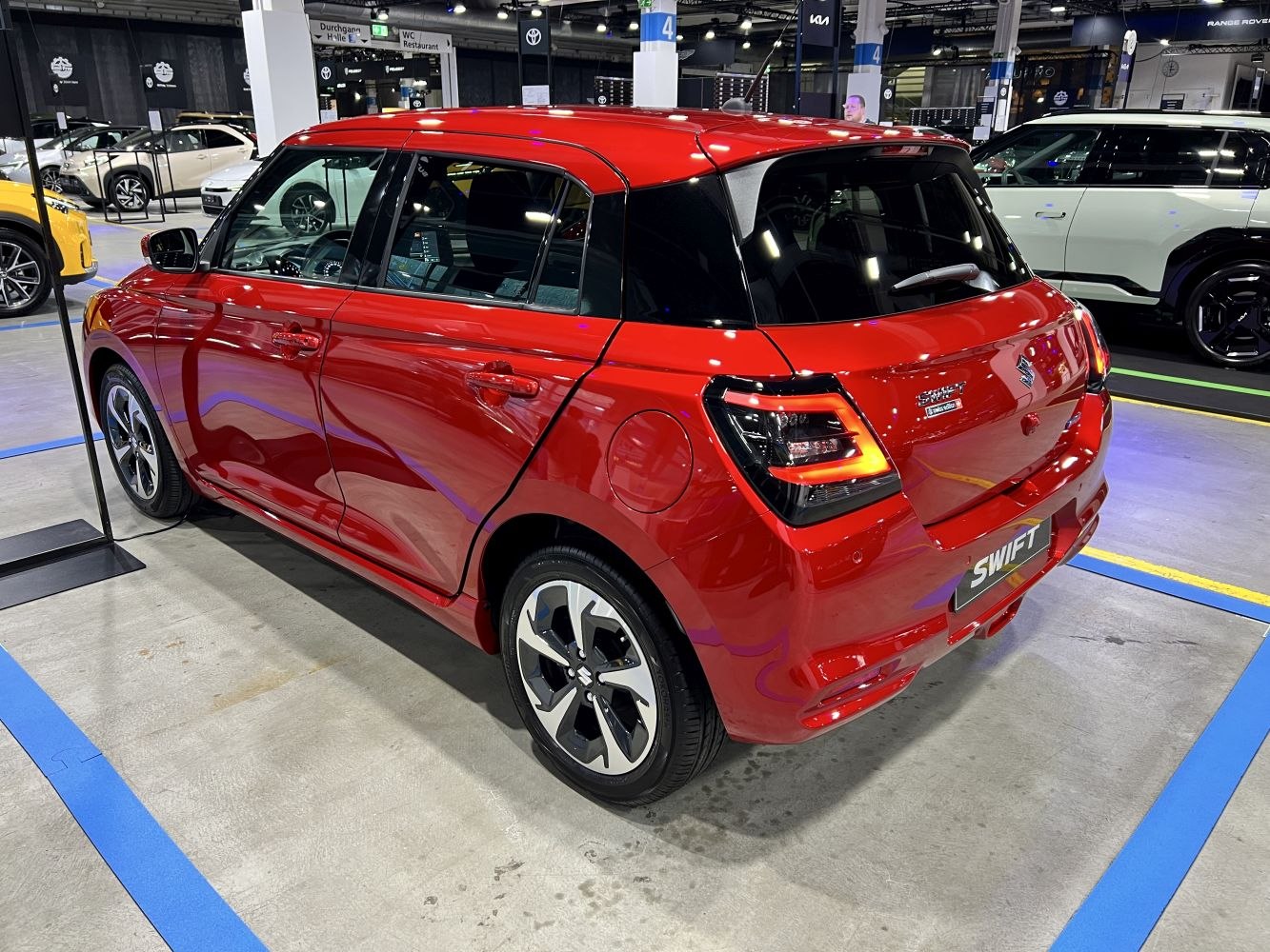 Rear and side view of a red compact hatchback with modern taillights and alloy wheels