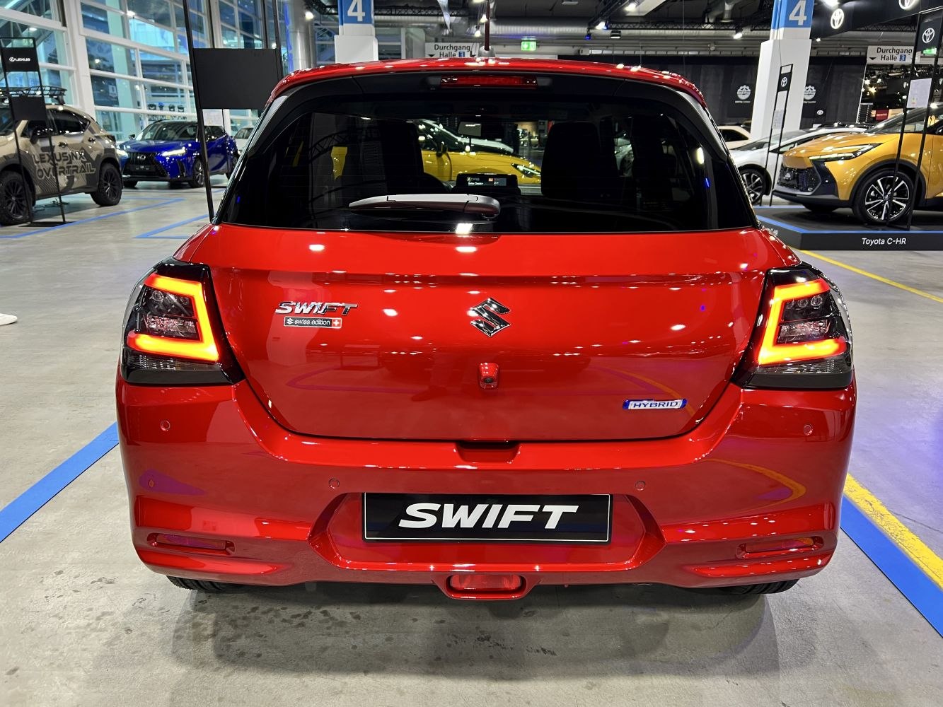 Rear view of a red compact hatchback with highlighted LED taillights and hybrid badge