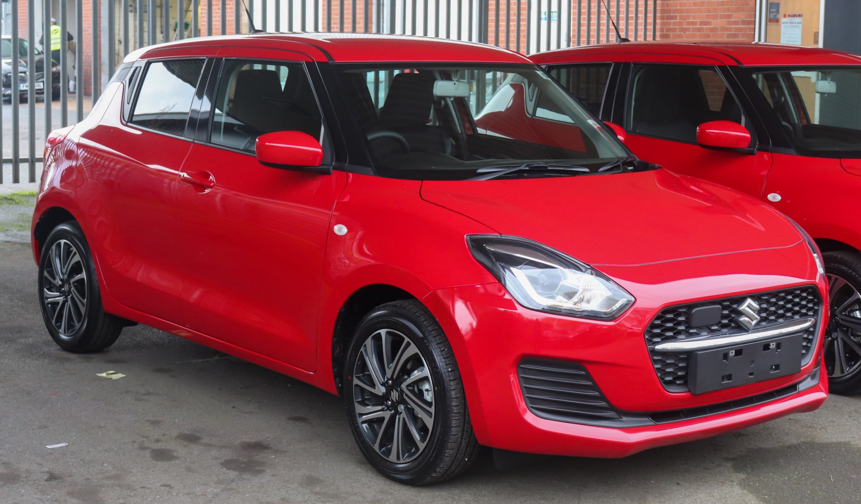 Red compact hatchback with sleek headlights and alloy wheels