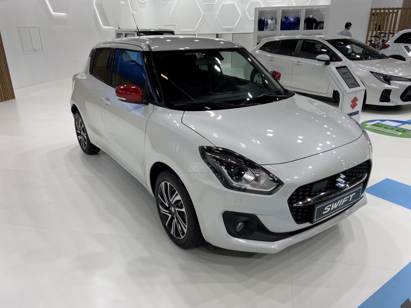 Front three-quarter view of a compact hatchback with sporty alloy wheels and red side mirrors.