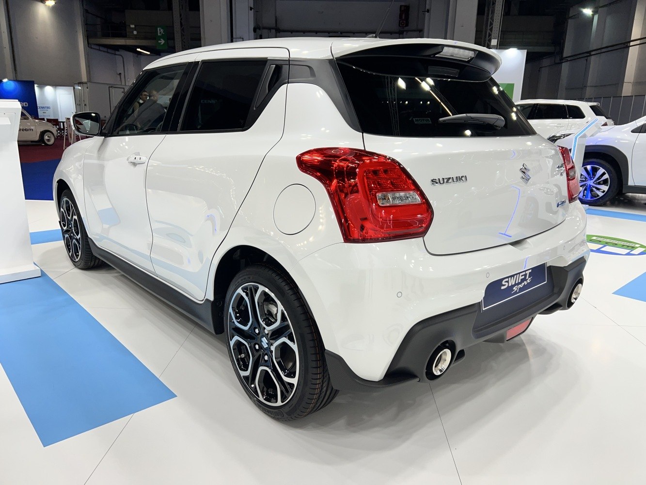Rear side view of white compact hatchback with sporty rims and dual exhausts