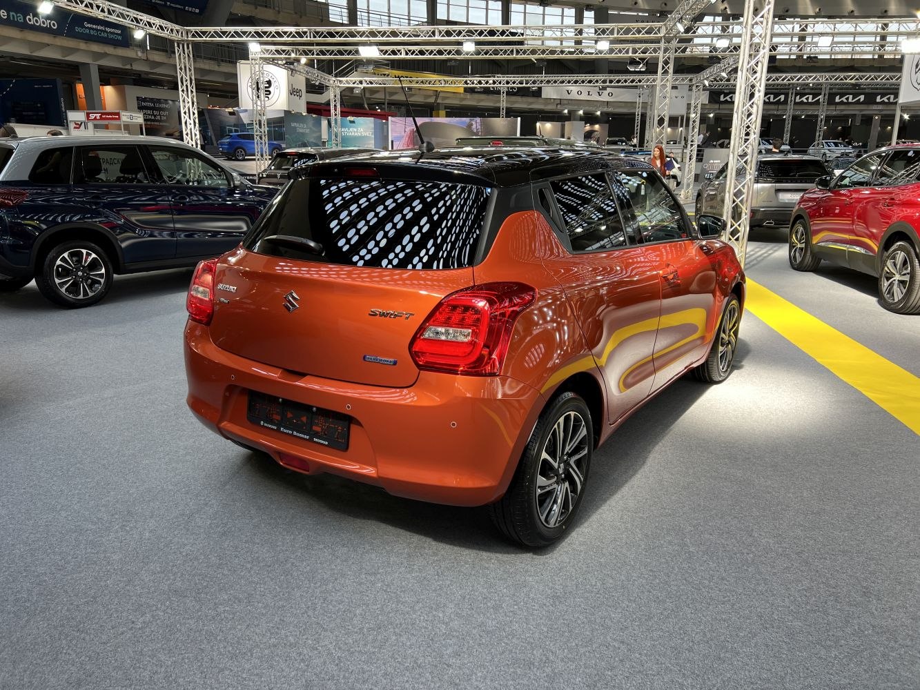 Orange compact hatchback rear and side view with tinted windows and alloy wheels.